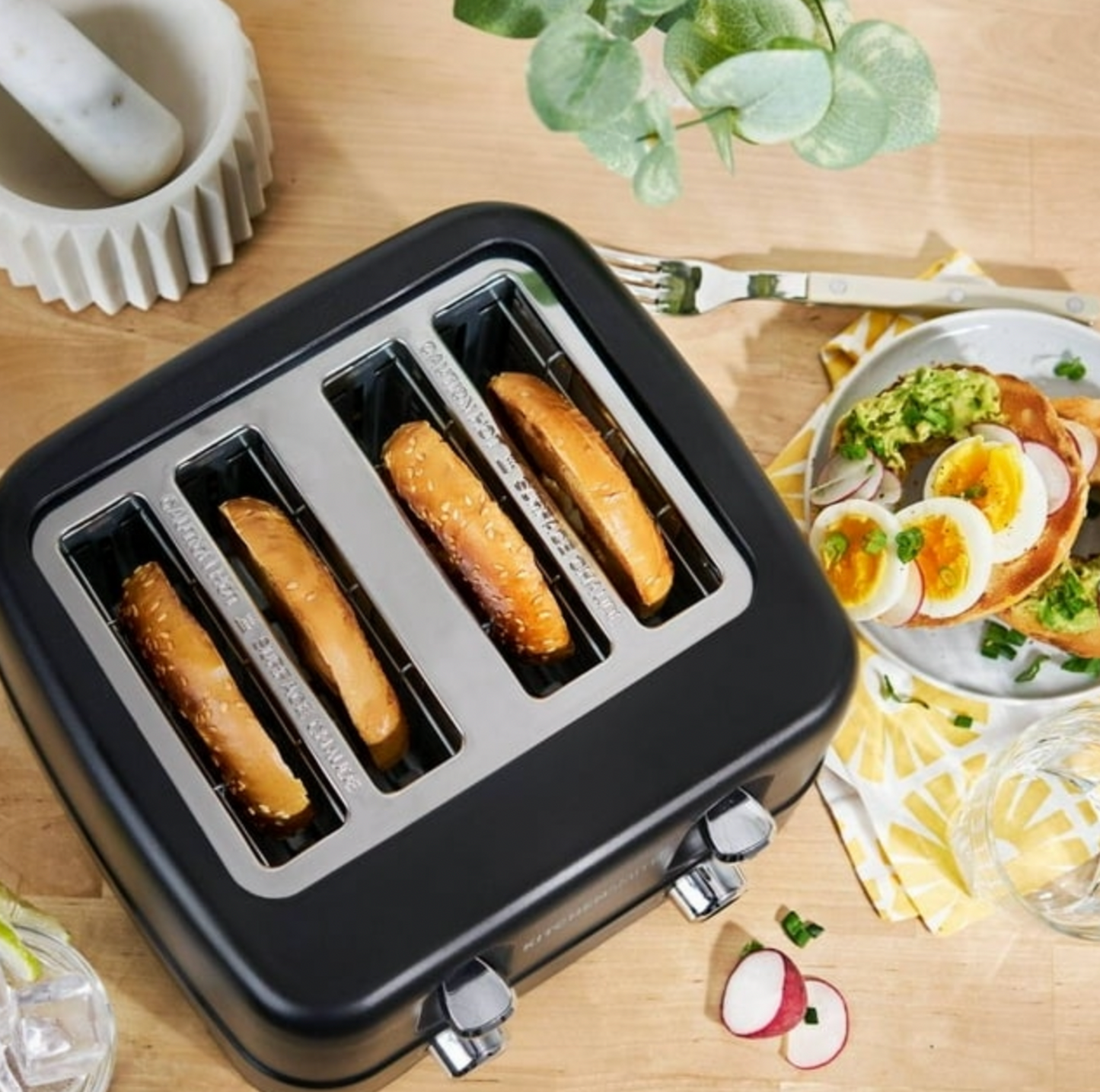 Vue de dessus du grille-pain noir 4 tranches avec rôties à côté d'une assiette de toasts à l'avocat