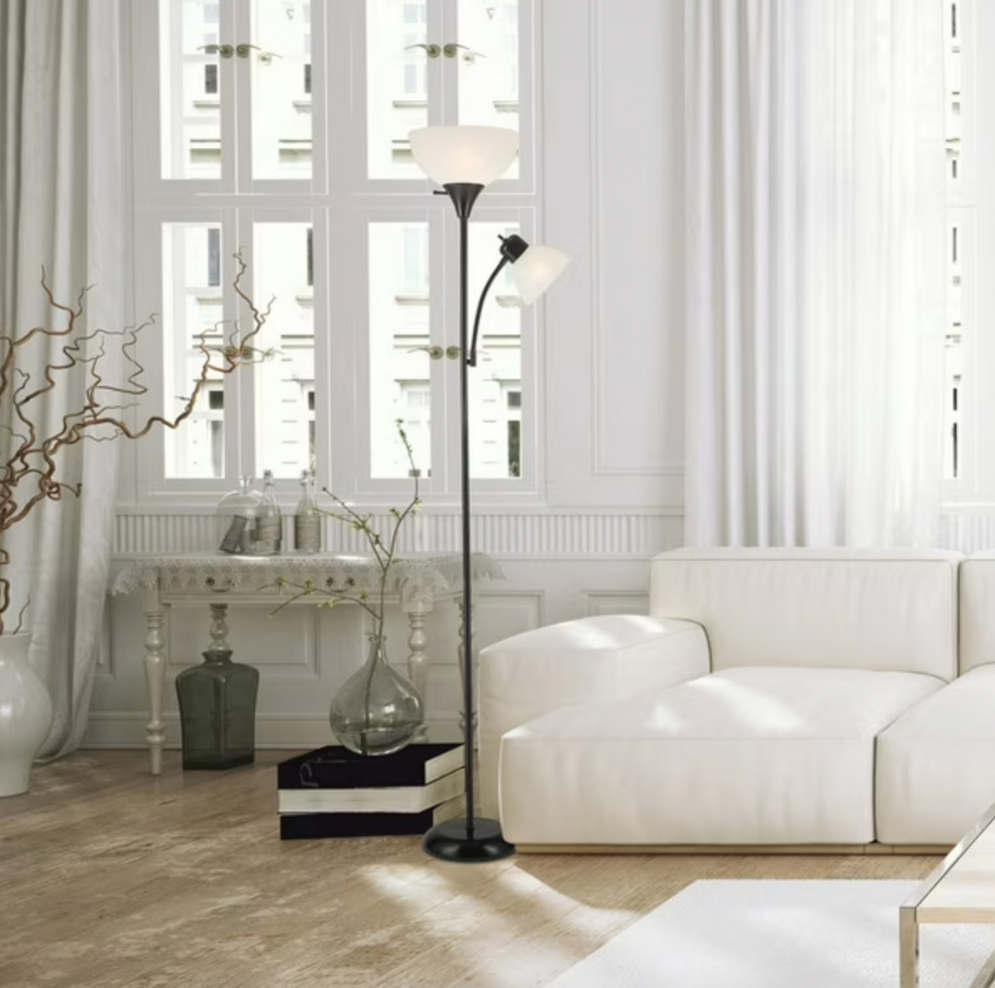 Lampadaire torchère Delilah noir éclairant un salon de style parisien avec canapé blanc et console