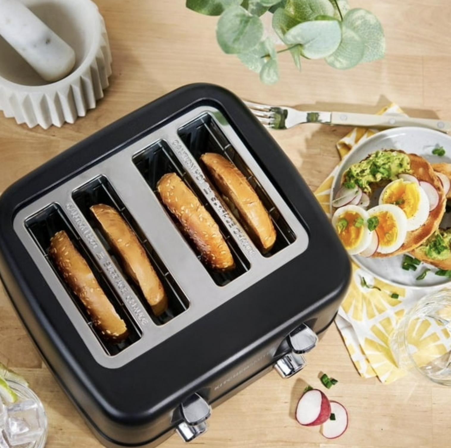 Vue de dessus du grille-pain noir 4 tranches avec rôties à côté d'une assiette de toasts à l'avocat