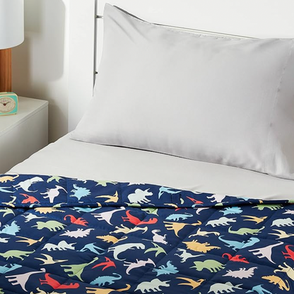 Navy blue dinosaur print weighted blanket on bed with white pillow in kids bedroom