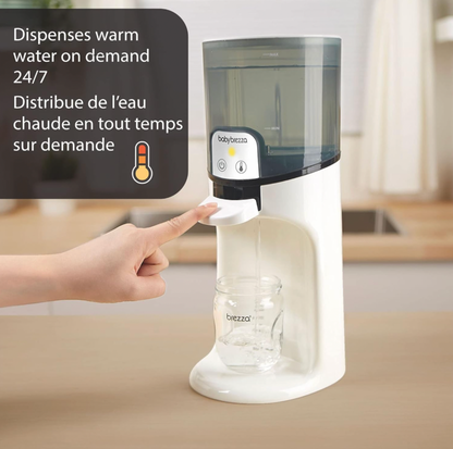 Main appuyant sur le bouton du chauffe-biberon Baby Brezza remplissant un biberon avec mention bilingue Distribue de l'eau chaude en tout temps sur demande
