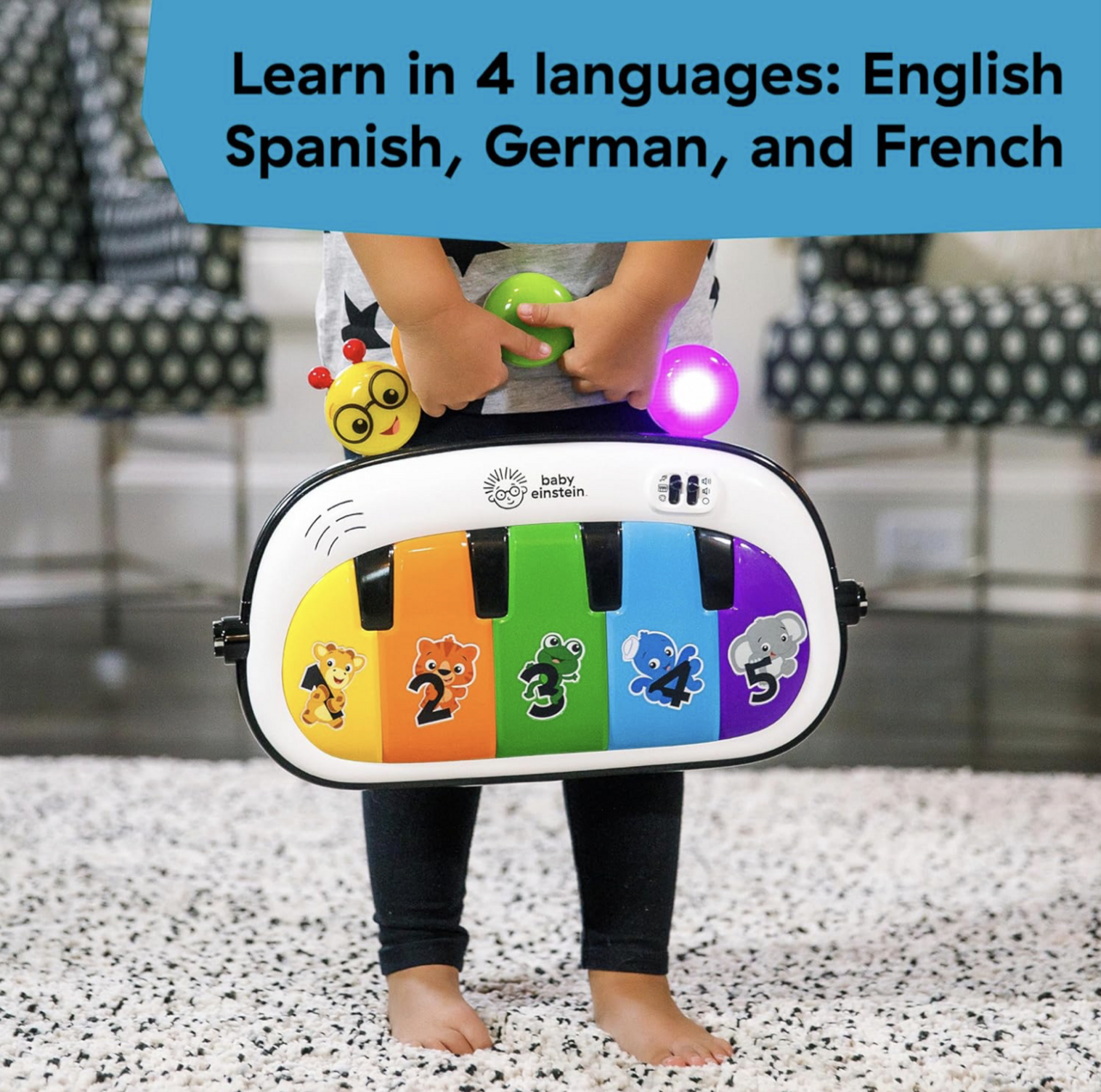 Enfant debout derrière le panneau piano multicolore Baby Einstein avec touches numérotées et illustrations d'animaux, mention Learn in 4 languages English Spanish German French