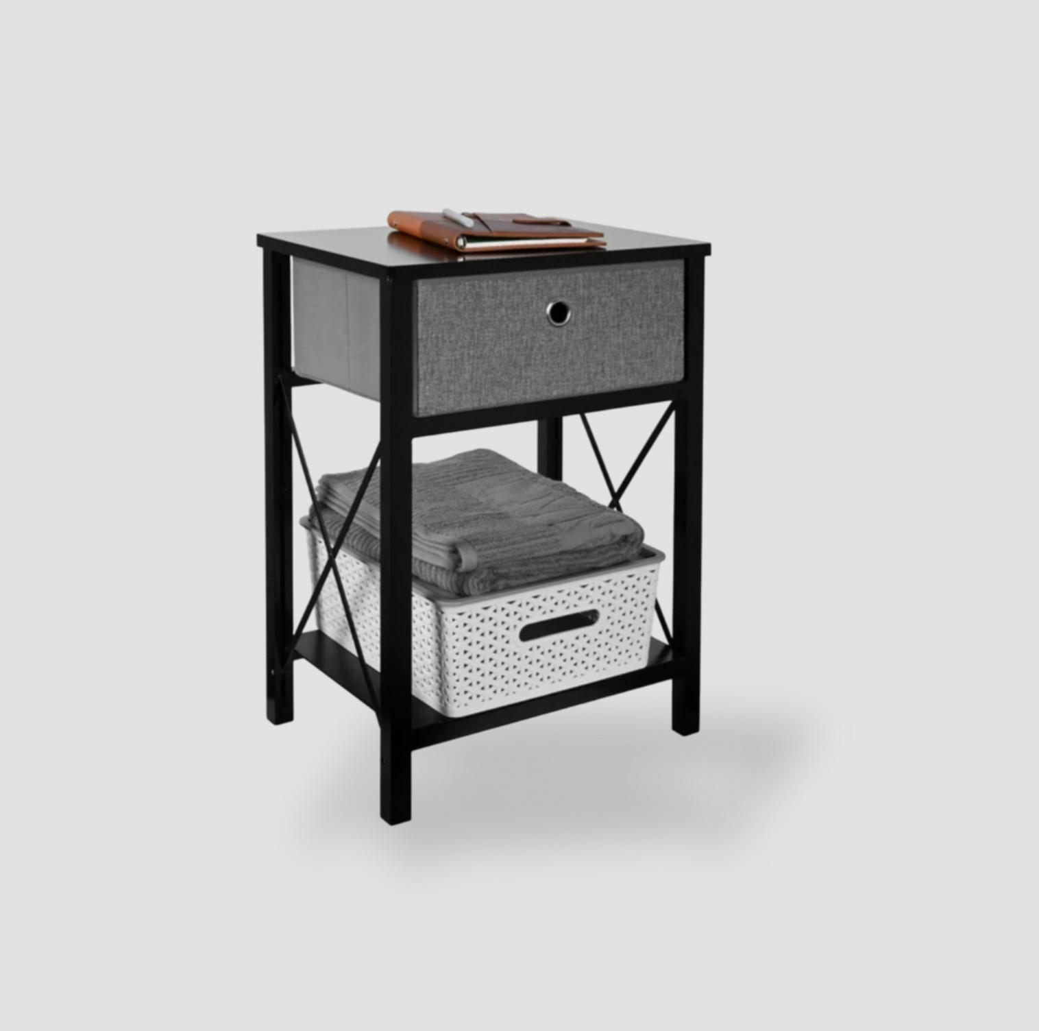 Vue trois-quarts de la table de chevet noire avec tiroir en tissu gris, tablette inférieure avec serviette pliée et panier blanc