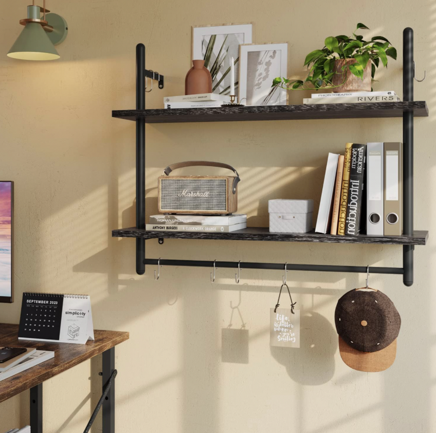 Étagère flottante industrielle 31 pouces Bestier noire à deux étages avec barre et crochets supportant haut-parleur, livres et plante dans un bureau à domicile