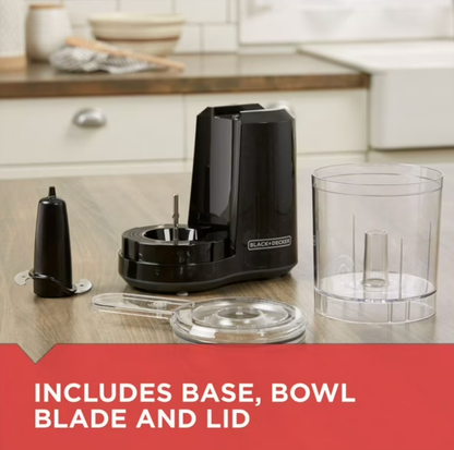 Mini robot culinaire BLACK+DECKER noir démonté sur comptoir en bois montrant base, bol transparent, couvercle et lame, mention Includes Base Bowl Blade and Lid