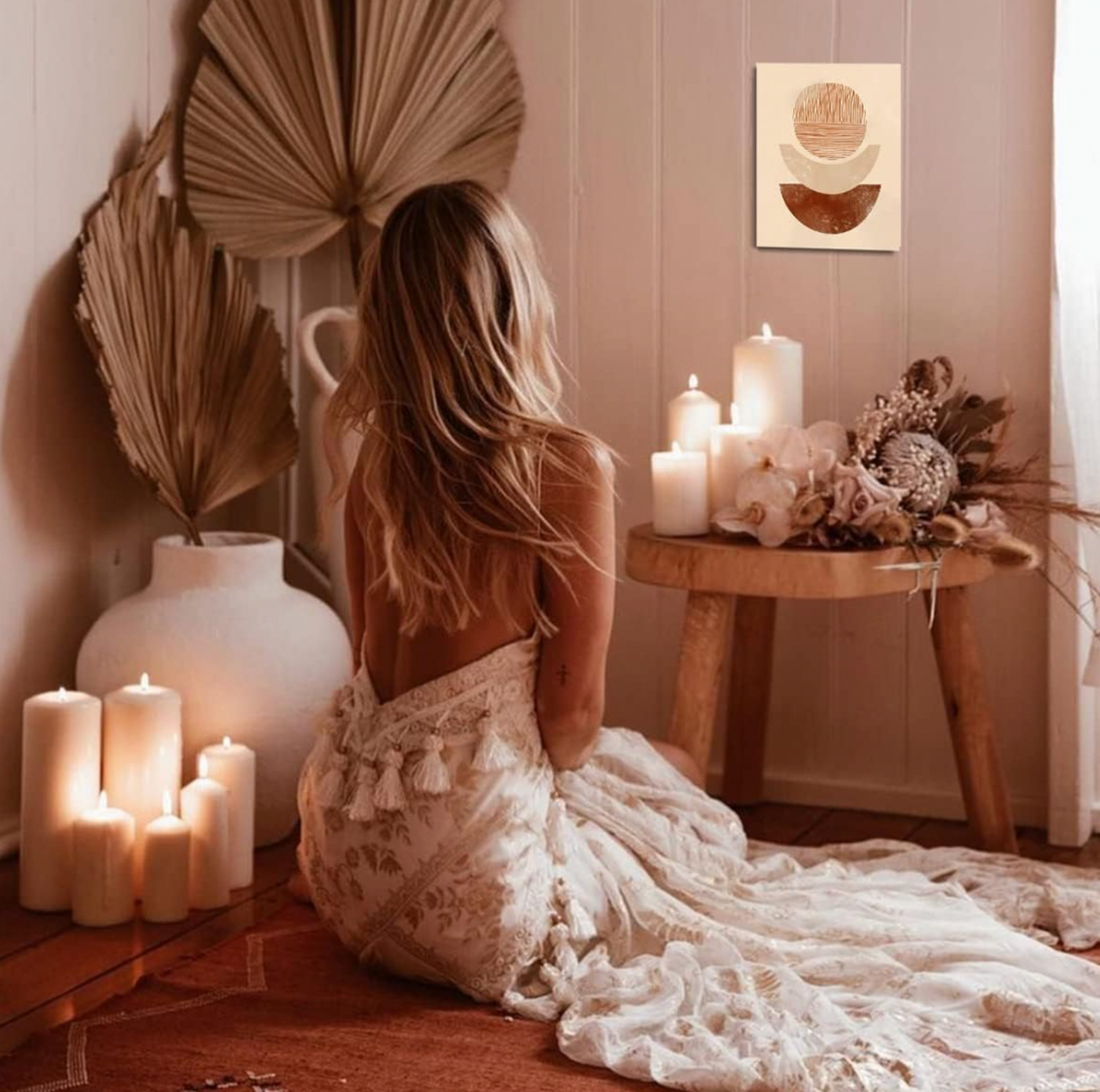 Toile bohème accrochée au mur dans une pièce cocooning avec feuilles de palmier, bougies et fleurs séchées