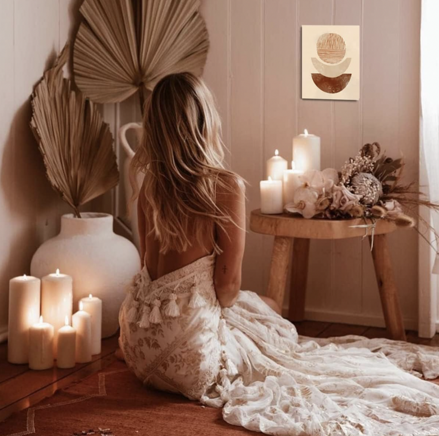 Toile bohème accrochée au mur dans une pièce cocooning avec feuilles de palmier, bougies et fleurs séchées