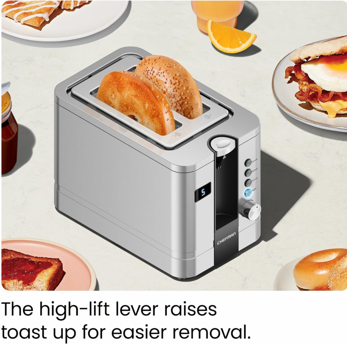Vue trois-quarts du grille-pain 2 tranches en acier inoxydable avec moitiés de bagel grillées soulevées entourées d'assiettes de petit-déjeuner, mention High-lift lever