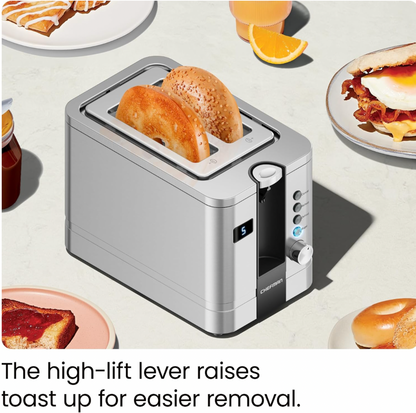 Vue trois-quarts du grille-pain 2 tranches en acier inoxydable avec moitiés de bagel grillées soulevées entourées d'assiettes de petit-déjeuner, mention High-lift lever