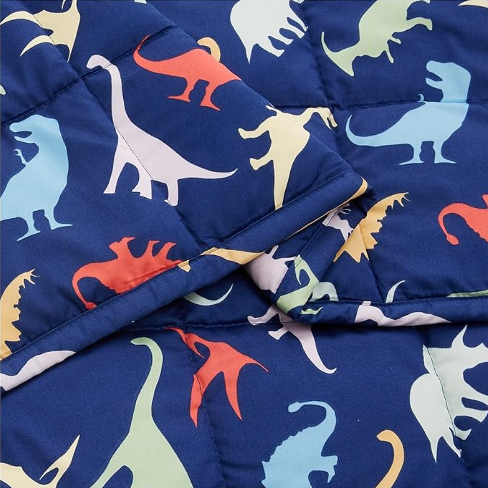 Close-up of dinosaur print cotton blanket showing colorful silhouettes and folded edge