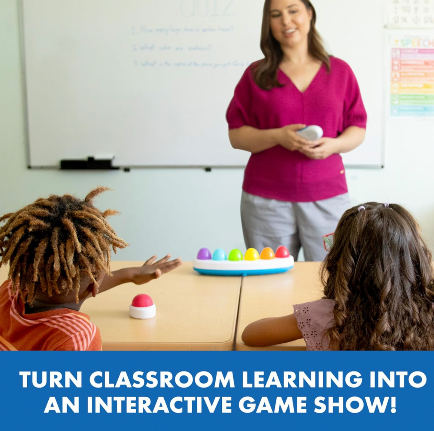 Enseignante en chemise rose tenant un buzzer Eggspert dans une salle de classe avec deux élèves assis au bureau avec la base de buzzer arc-en-ciel, mention Turn Classroom Learning Into an Interactive Game Show