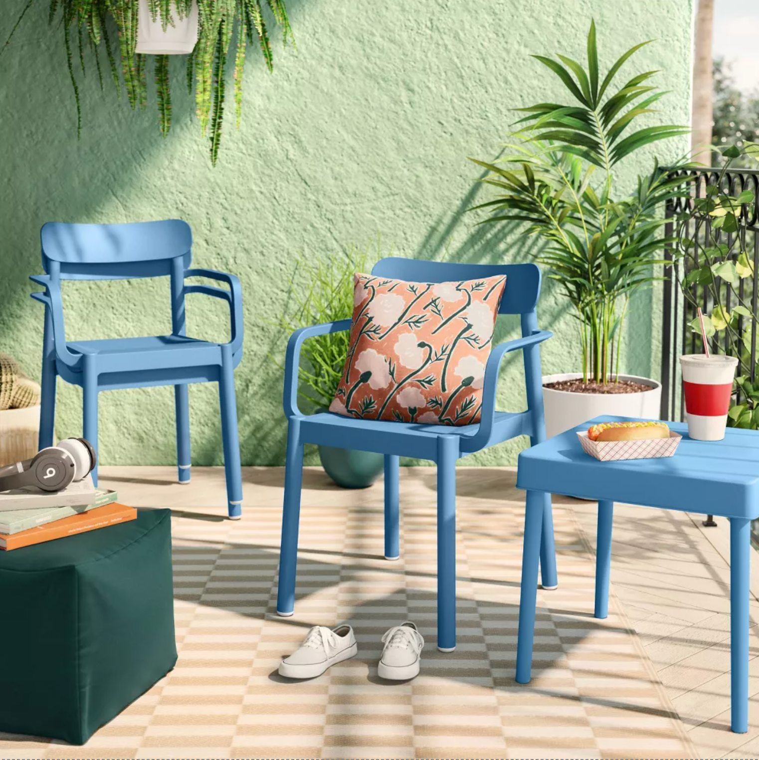 Deux chaises de patio Elba bleues sur une terrasse avec coussin floral, table d'appoint et plante à feuillage vert