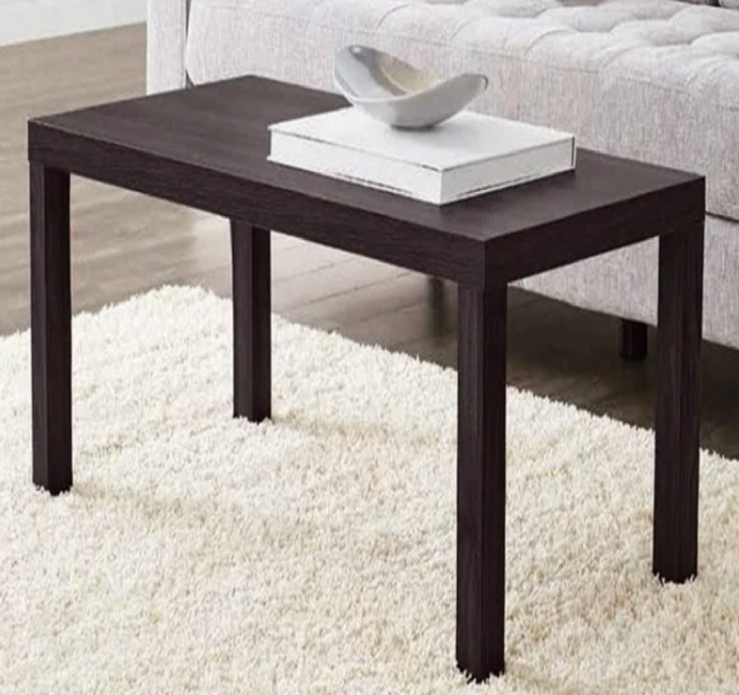 Table basse rectangulaire espresso foncé dans un salon avec canapé crème capitonné et tapis shaggy
