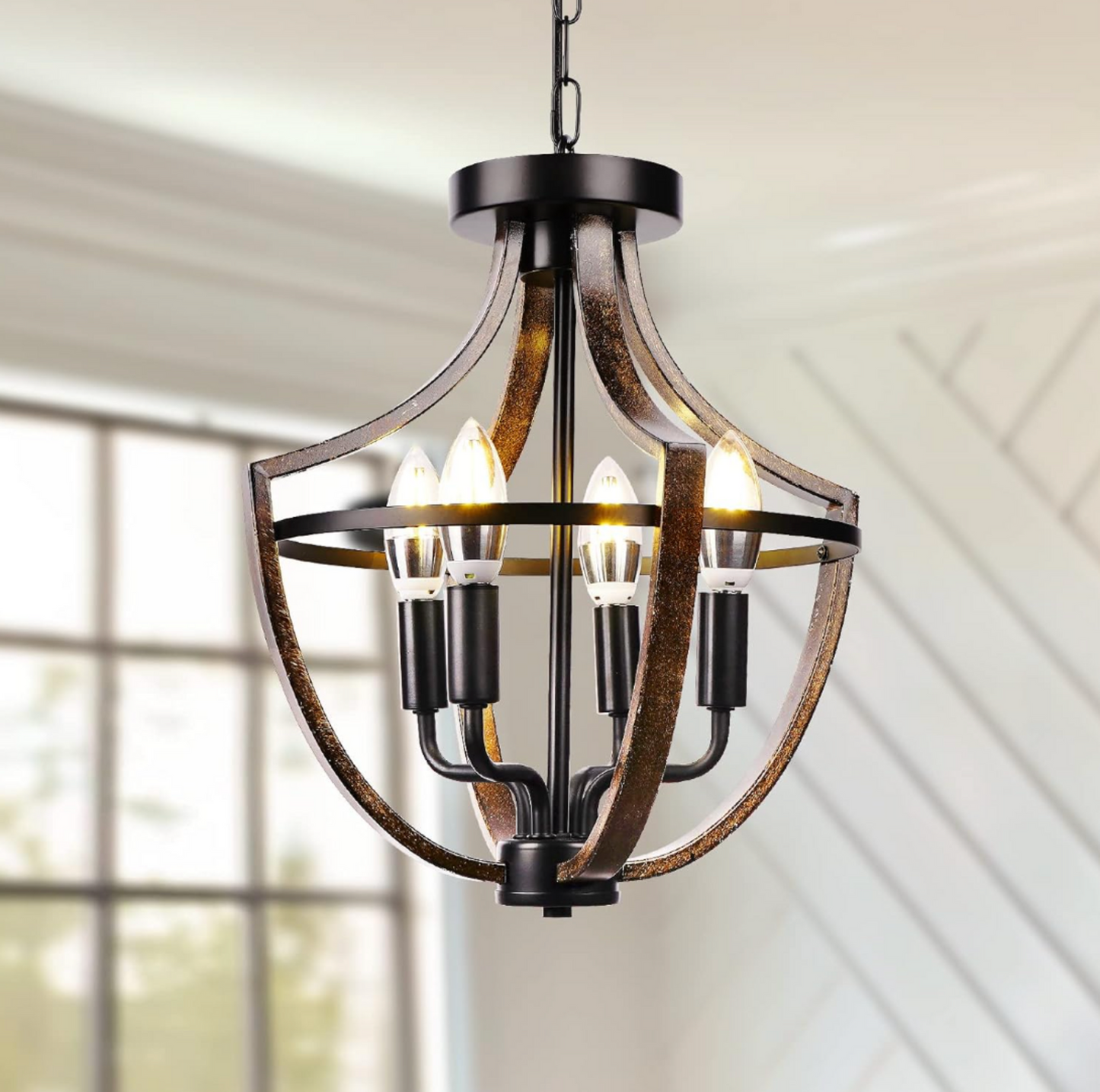 Gros plan du lustre suspendu cage 4 lumières style ferme avec quatre ampoules en forme de bougie allumées, arches incurvées effet bois foncé et structure en métal noir