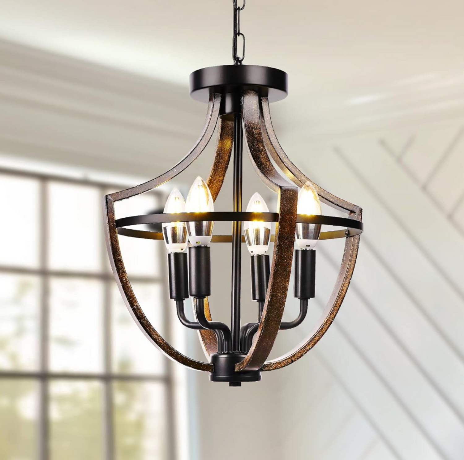 Gros plan du lustre suspendu cage 4 lumières style ferme avec quatre ampoules en forme de bougie allumées, arches incurvées effet bois foncé et structure en métal noir