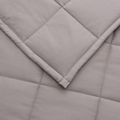Gros plan d'un coin de couverture lestée matelassée grise avec piqûres carrées et ourlet replié