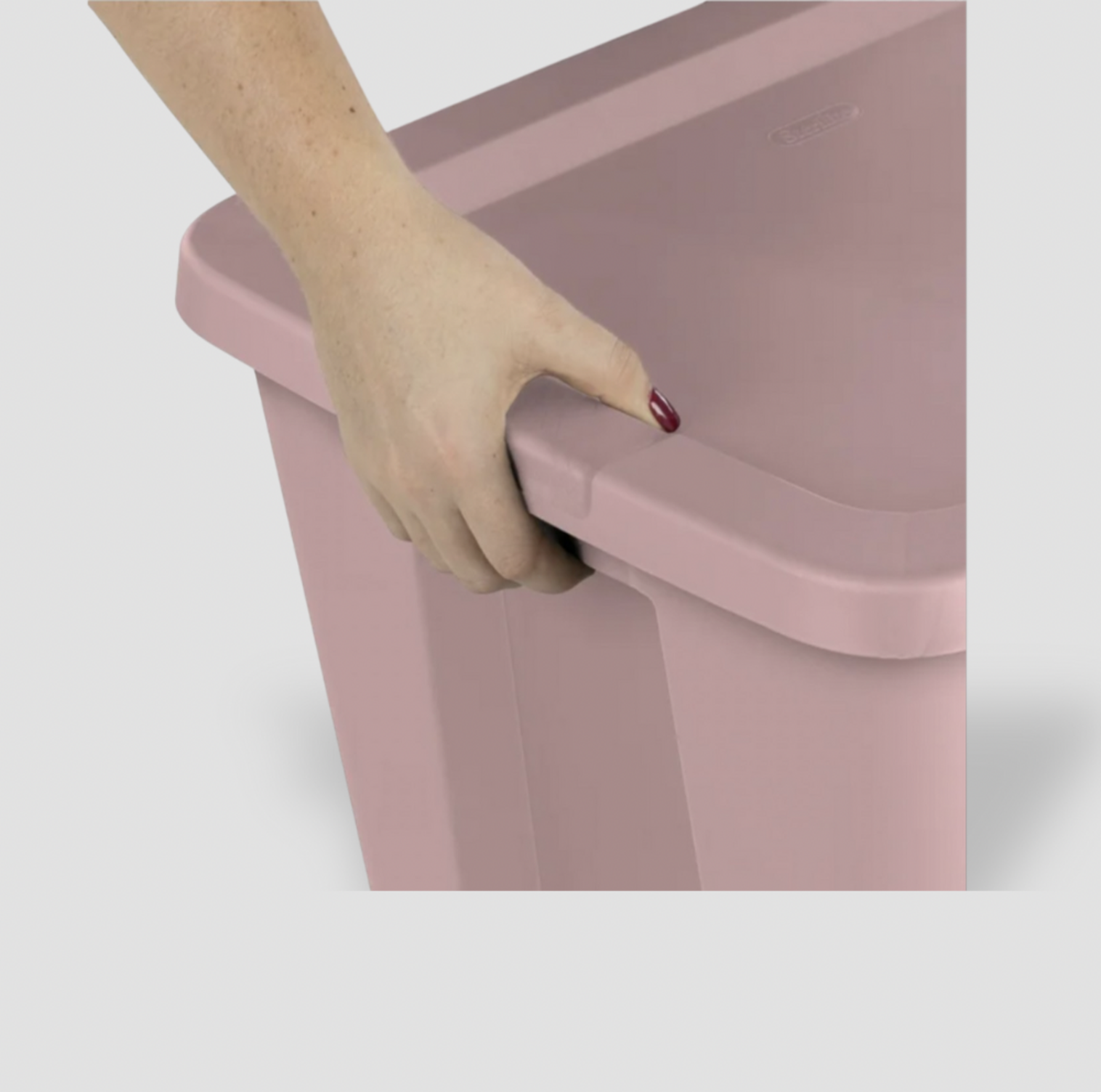 Main saisissant la poignée moulée latérale d'une boîte de rangement en plastique rose pâle