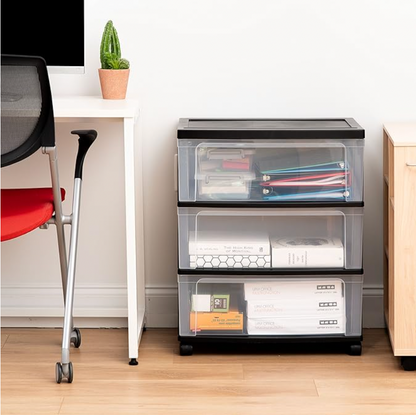 Chariot à 3 tiroirs noir sur roulettes dans un bureau à domicile avec dossiers, papiers et fournitures à côté d'une chaise rouge