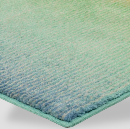 Gros plan d'un coin du tapis bordé avec poil touffeté vert vers bleu et bordure surfilée assortie