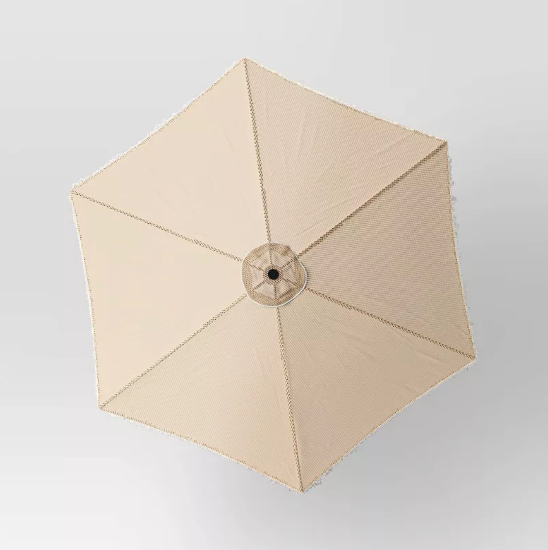 Vue de dessus de la toile hexagonale beige du parasol montrant six panneaux et bordure à franges