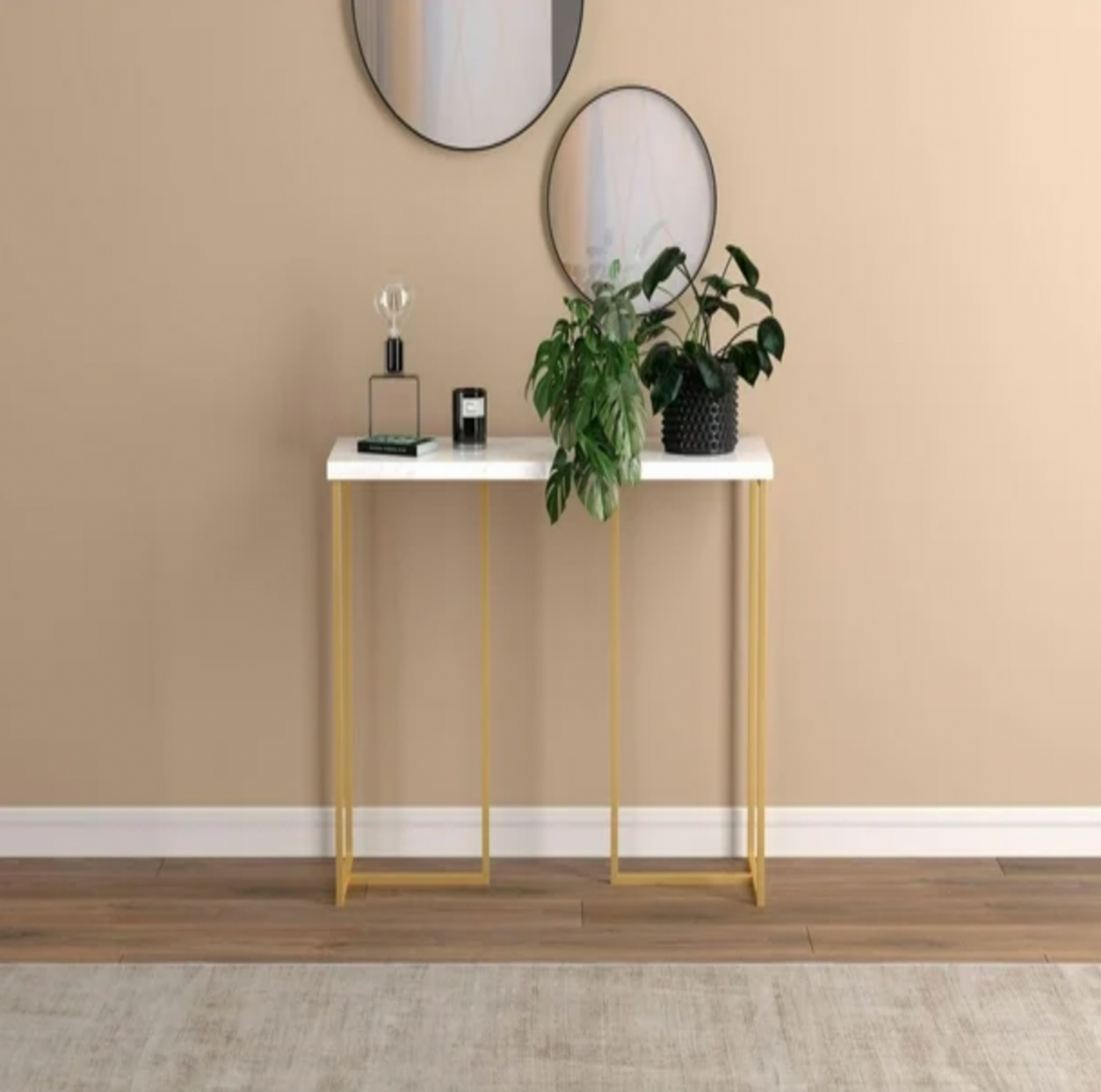 Table console en marbre et doré mise en scène dans une entrée avec miroirs ronds, bougie et plante en pot