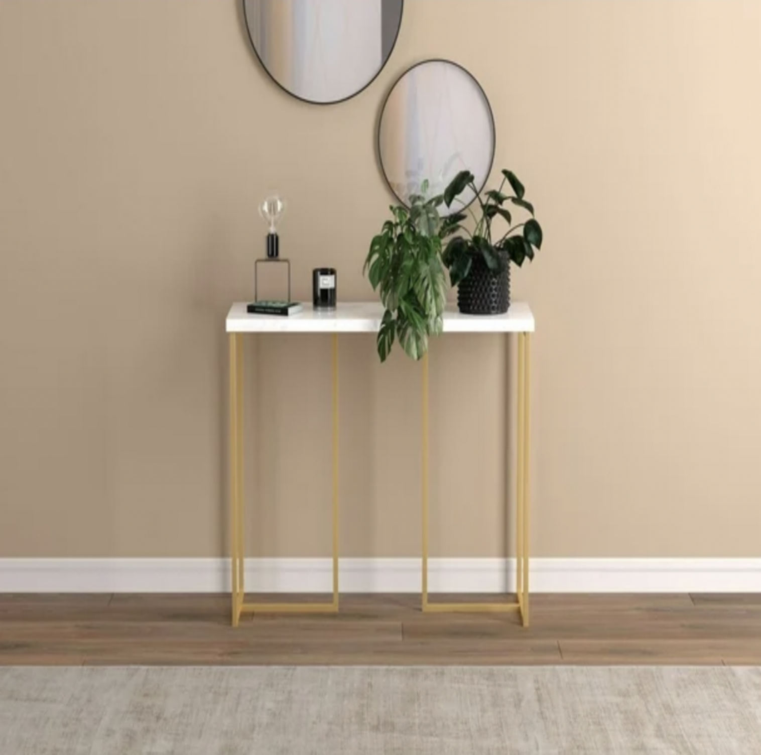 Table console en marbre et doré mise en scène dans une entrée avec miroirs ronds, bougie et plante en pot