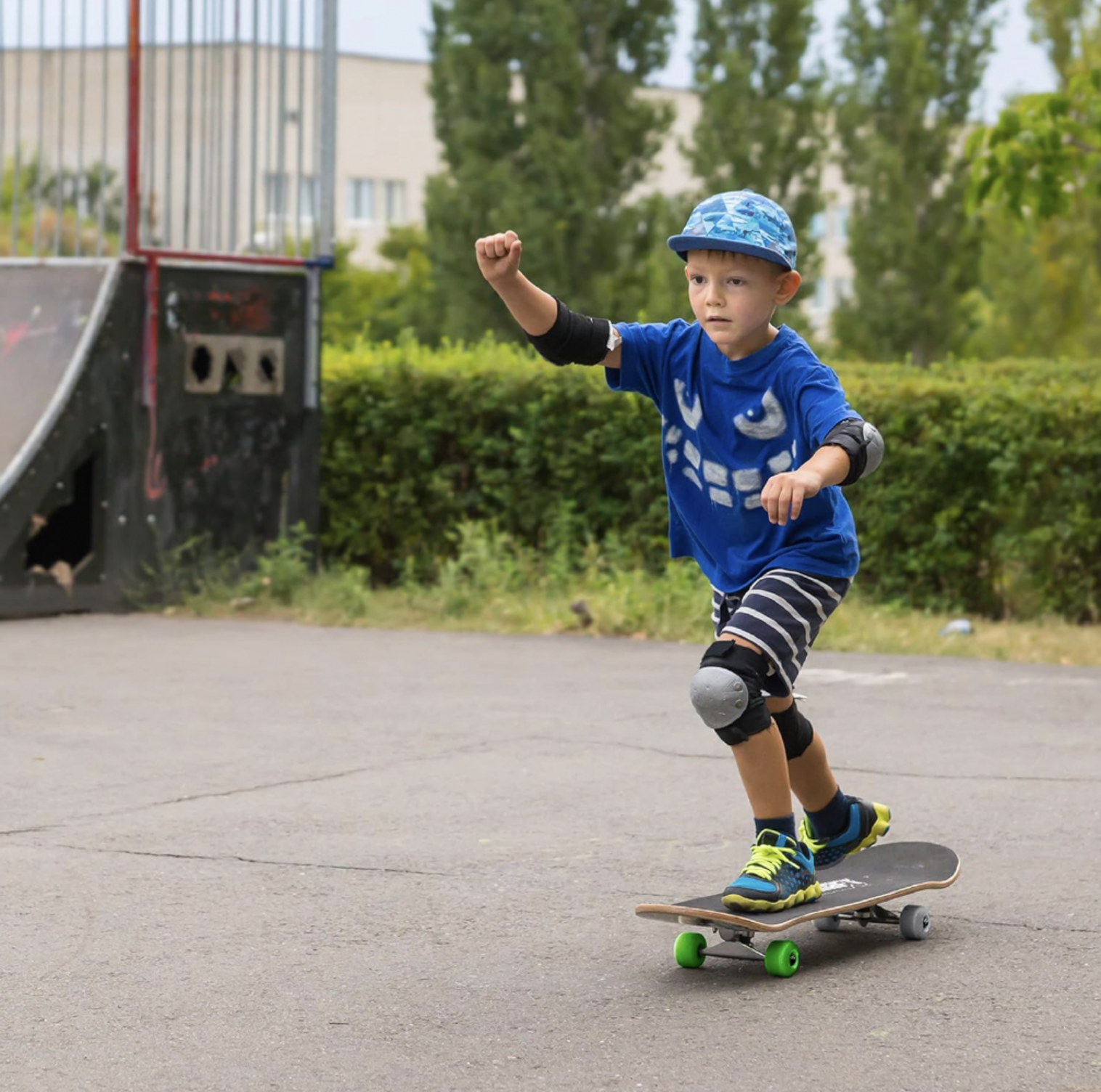 Garçon en chandail bleu et chapeau bob roulant sur une planche à roulettes Minecraft à roues vertes dans un skate parc