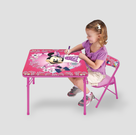 Young girl drawing at pink Minnie Mouse square activity table with matching pink folding chair in playroom