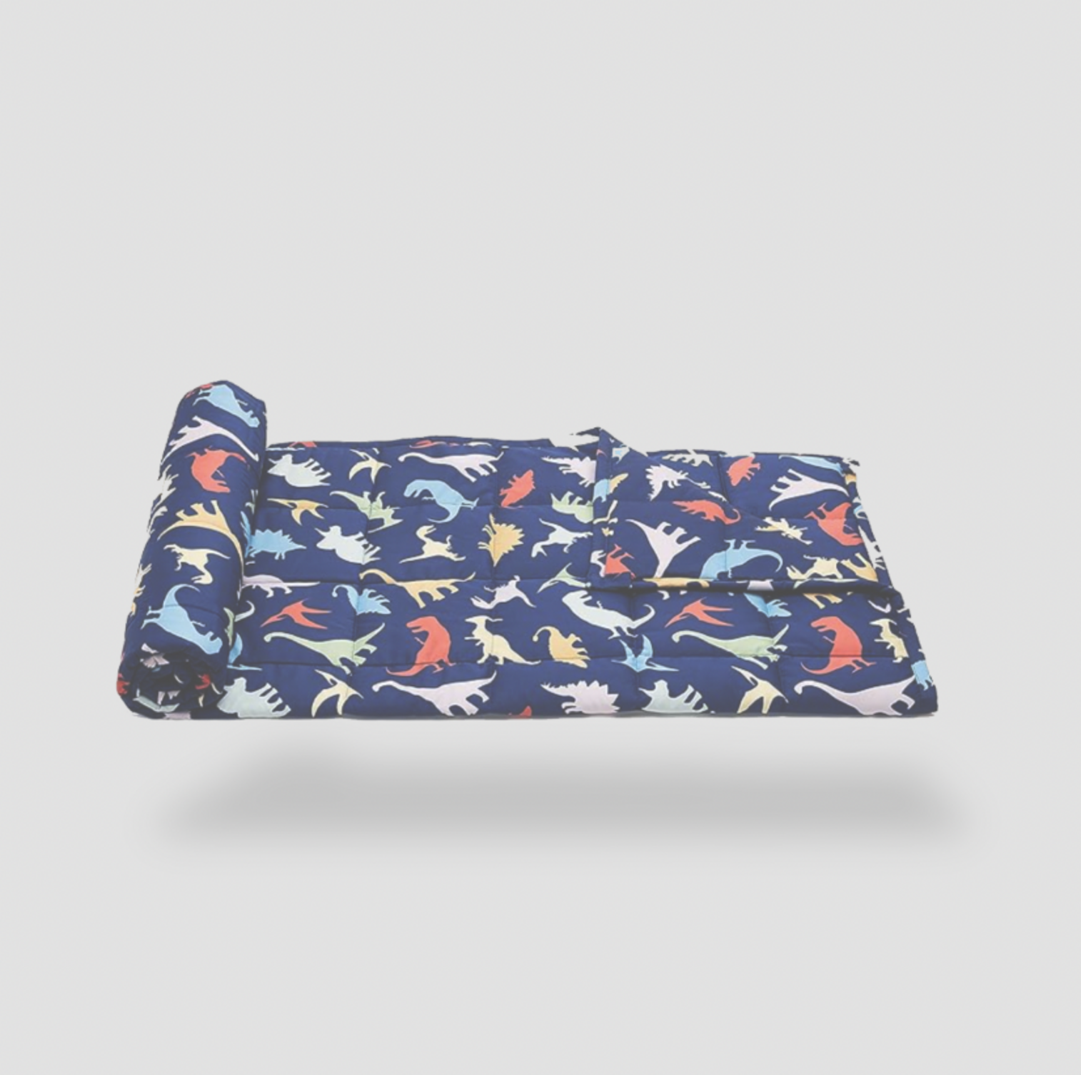 Half-rolled navy dinosaur kids blanket on white background, side view of quilted weave