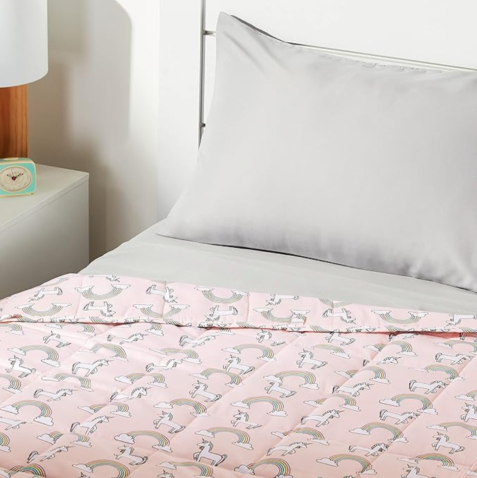 Pink unicorn kids weighted blanket on bed with gray pillow in bedroom