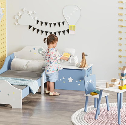 Fillette plaçant un livre sur le coffre à jouets bleu dans une chambre d'enfant avec décor mural de nuage et ballon et tableau perforé