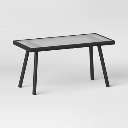 Table basse rectangulaire d'extérieur noire avec plateau en verre texturé et pieds inclinés en acier, vue trois-quarts