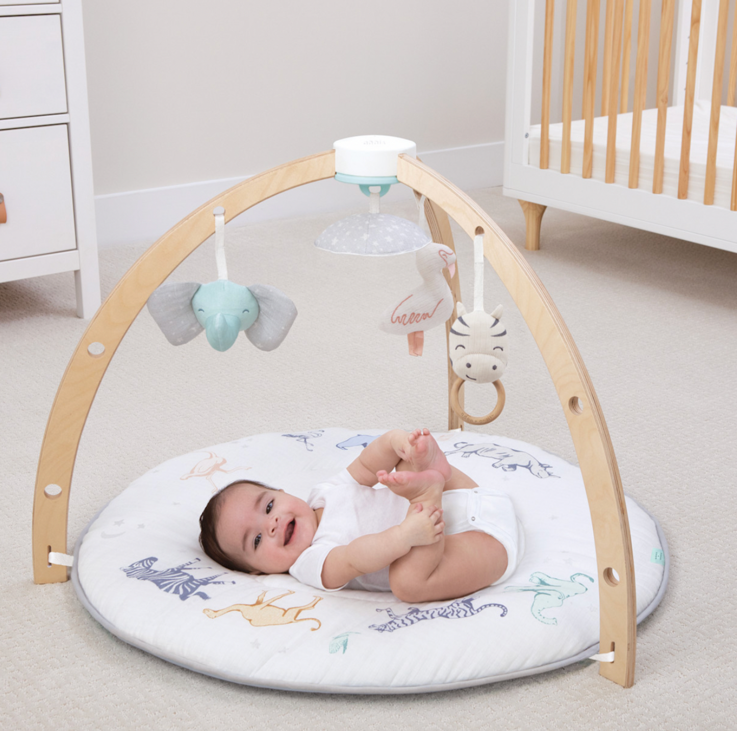 Bébé jouant sur le tapis d'éveil rond Rising Star à imprimé safari avec arches en bois, éléphant, zèbre et projecteur