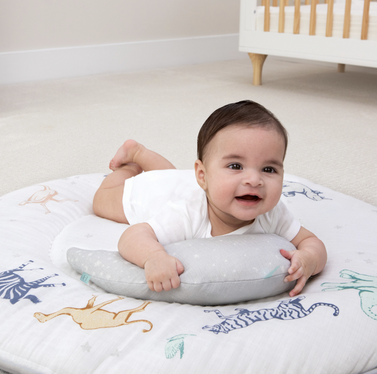Bébé sur le ventre sur le tapis d'éveil safari Rising Star avec coussin de soutien lune gris dans une chambre de bébé