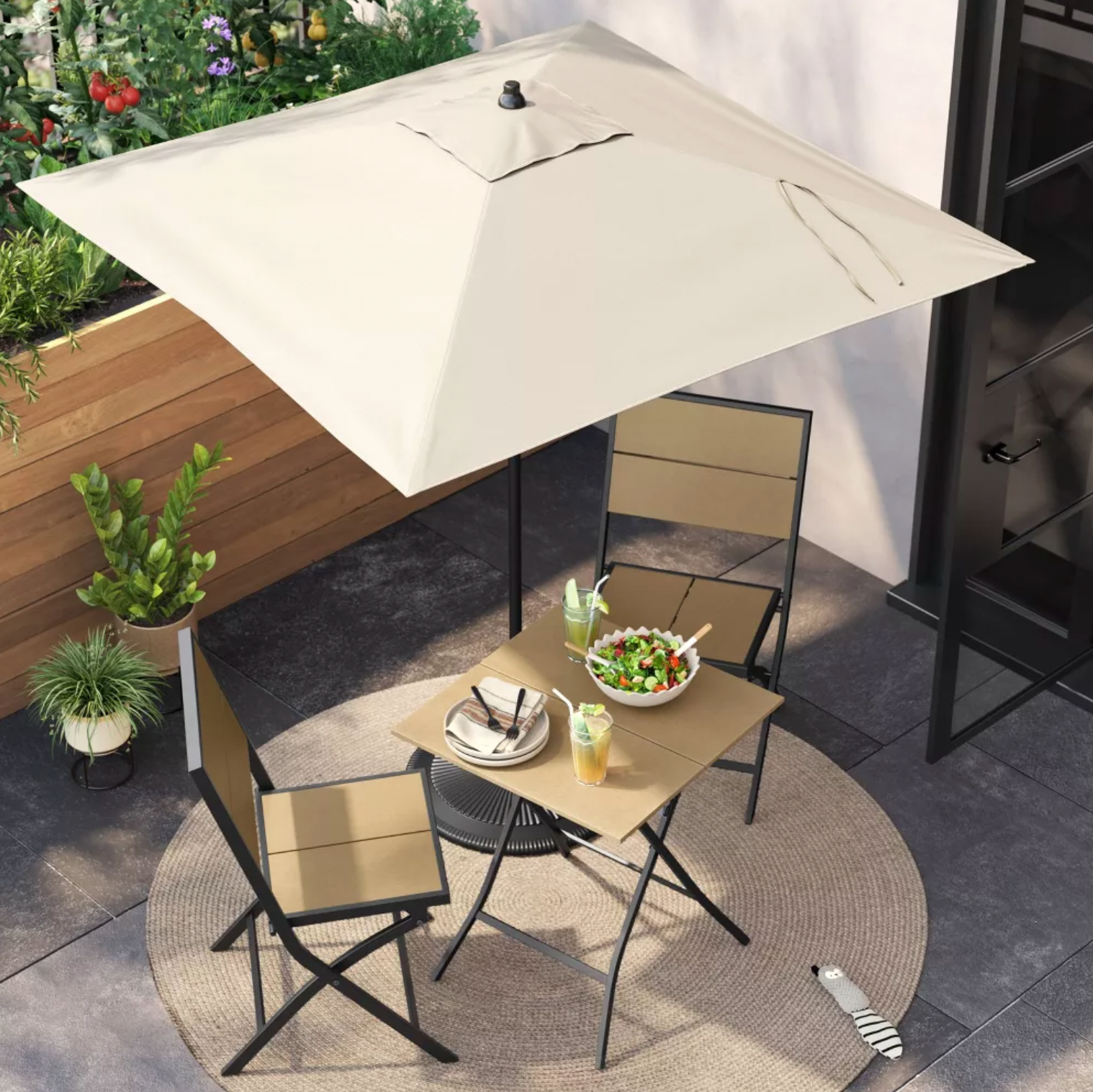 Vue en plongée d'un parasol de patio carré beige ombrageant un ensemble bistro avec salade et boissons