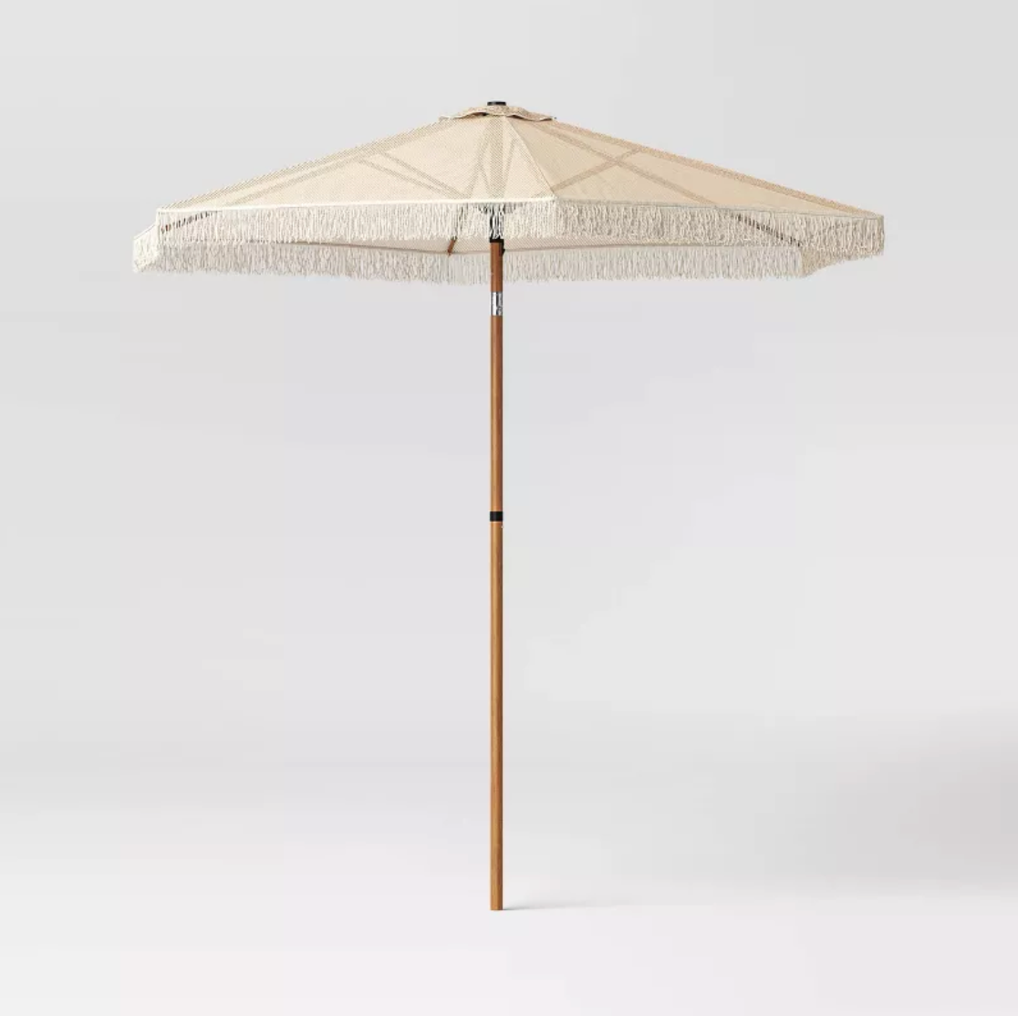 Parasol de patio en macramé beige avec toile hexagonale, frange et mât en faux bois, vue trois-quarts