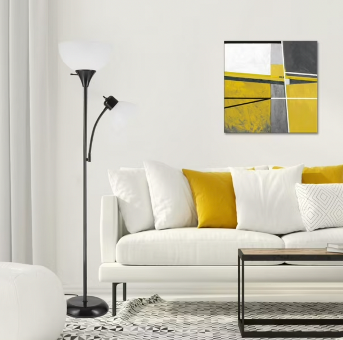 Lampadaire torchère noir à côté d'un canapé blanc avec coussin jaune et oeuvre murale abstraite