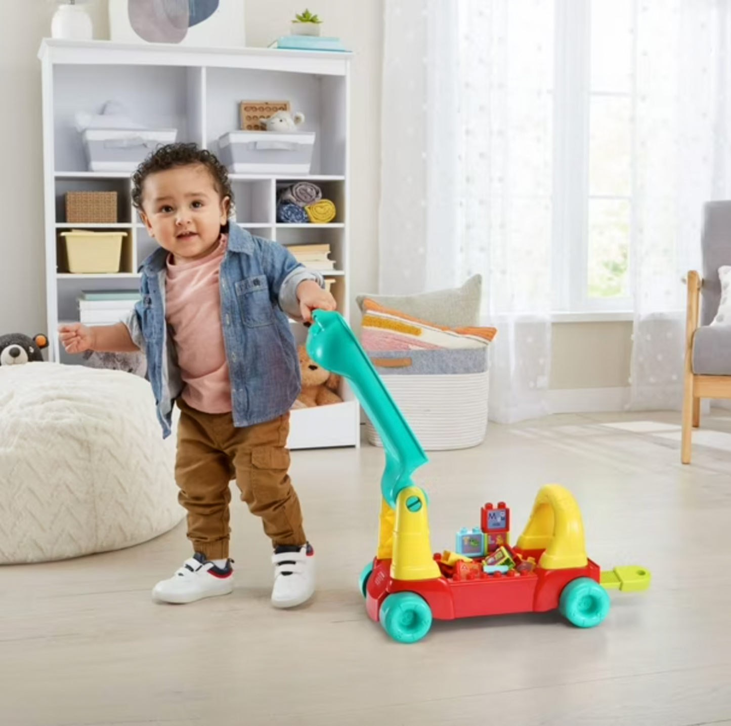 Boy holding teal handle of VTech learning train wagon with alphabet blocks in nursery