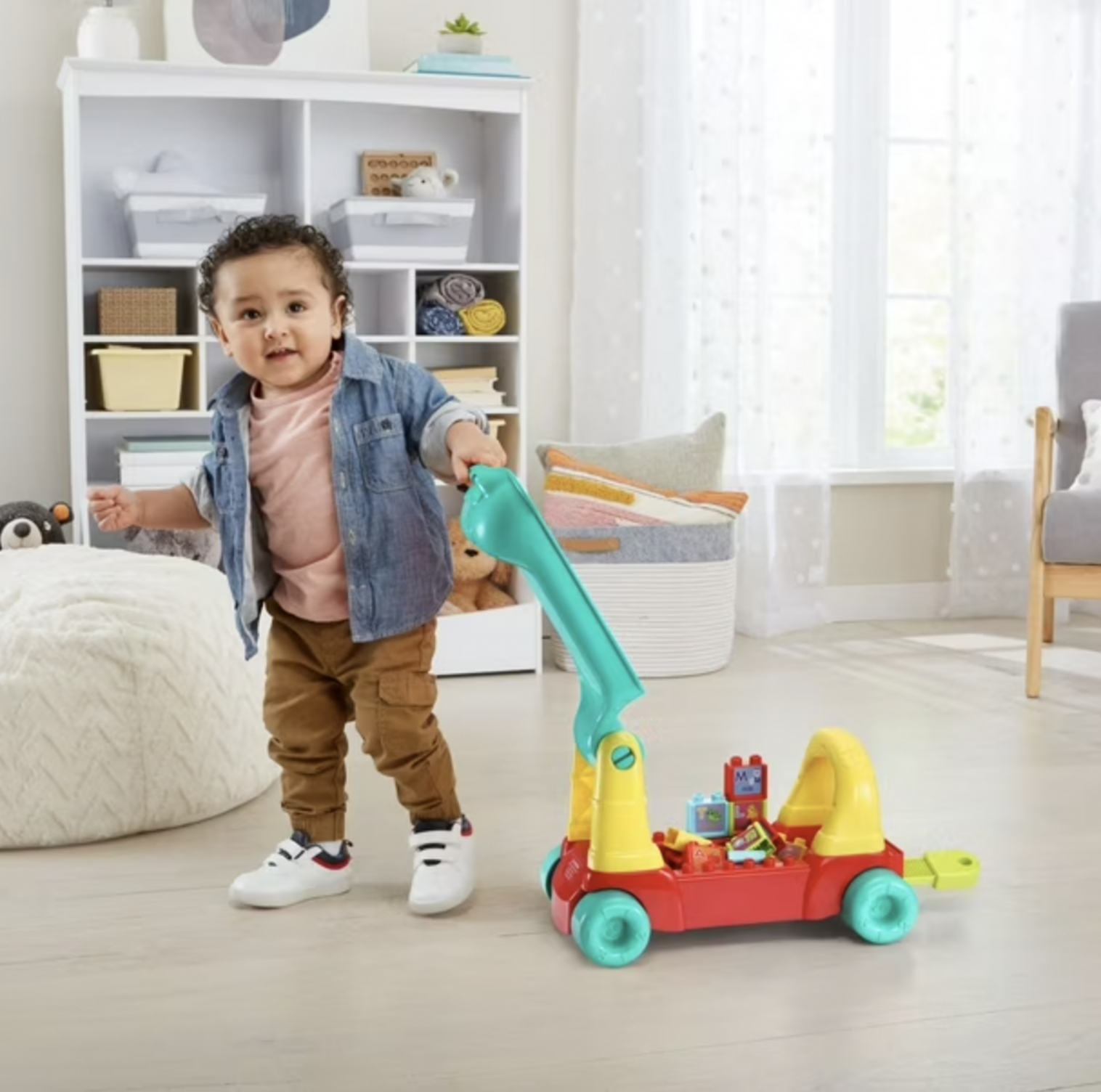 Boy holding teal handle of VTech learning train wagon with alphabet blocks in nursery