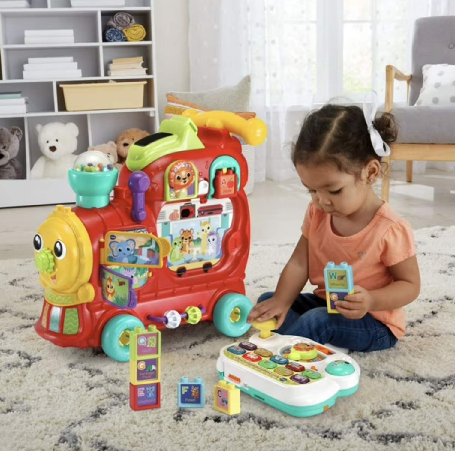 Toddler girl playing with VTech train detachable activity panel and alphabet blocks on rug