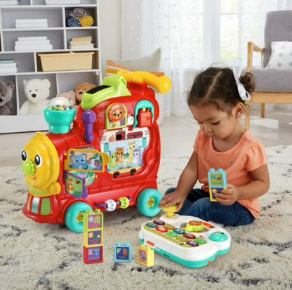 Toddler girl playing with VTech train detachable activity panel and alphabet blocks on rug