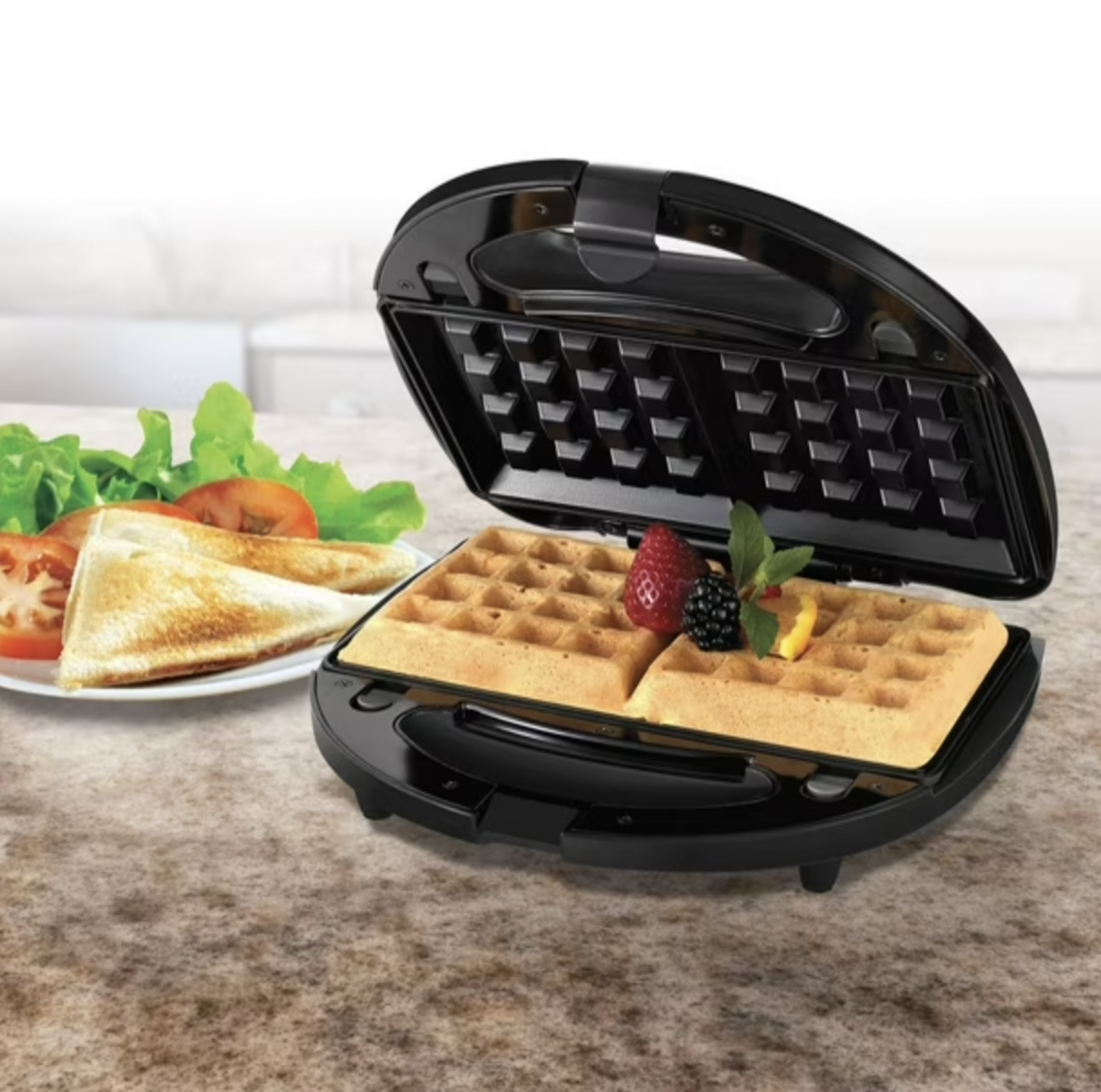 Gaufrier ouvert avec deux gaufres dorées garnies de fruits rouges et sandwich grillé avec laitue et tomate dans une assiette à côté