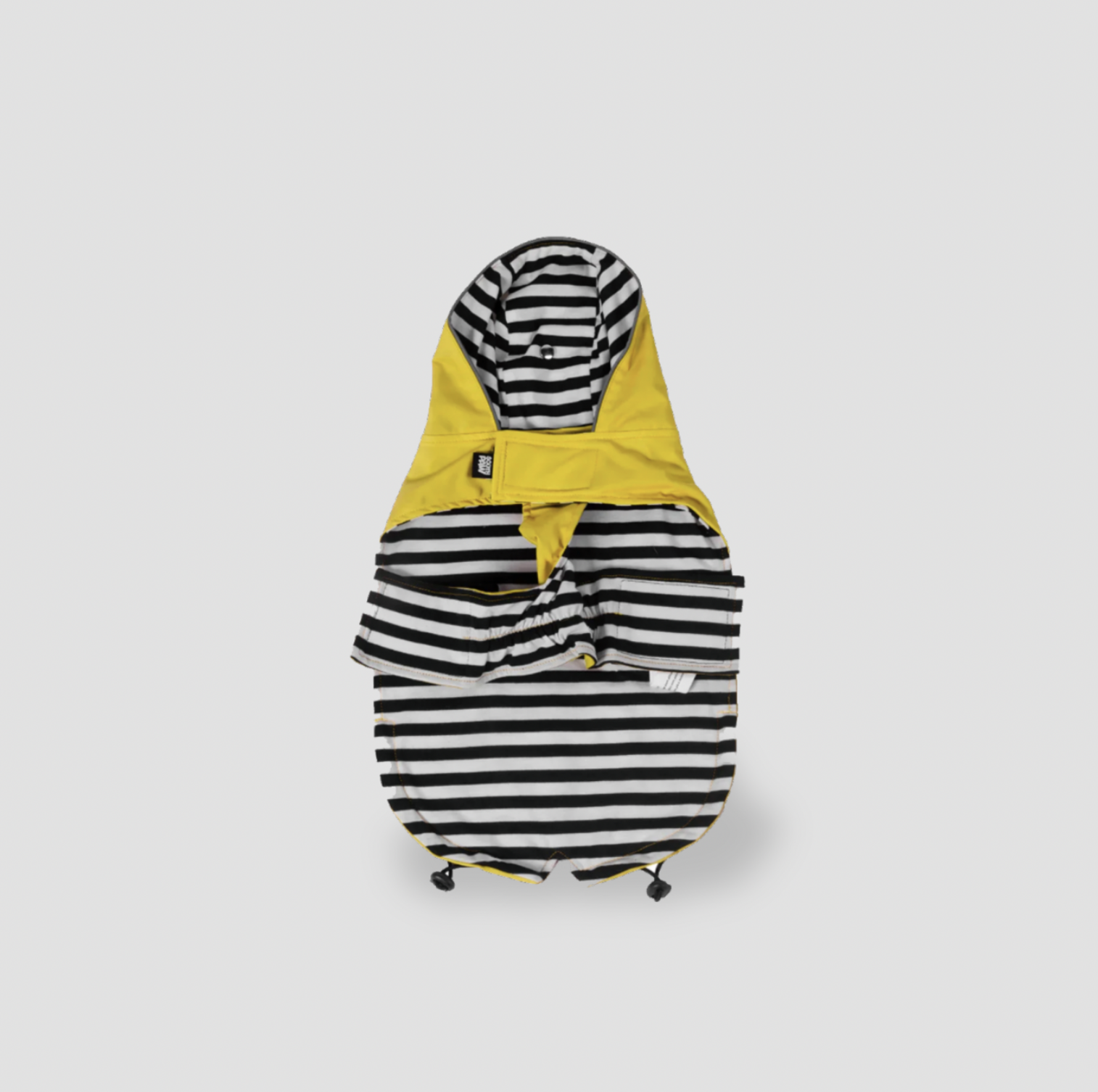 Imperméable jaune à capuche pour chien posé à plat montrant le dessous rayé noir et blanc